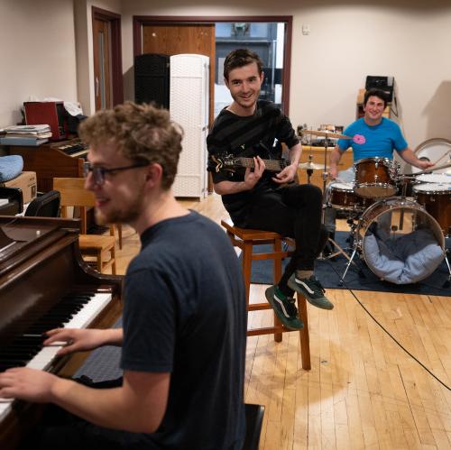 三名学生在枫叶工作室演奏鼓、吉他和钢琴.